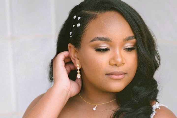 African American bride with soft glam makeup, hair style in soft Hollywood waves with a side part and pearl accessories on the side part
